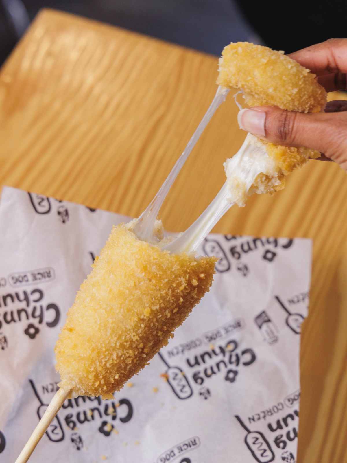 Cheese-pull : un Rice Dog Chungchun ouvert en deux, mozzarella filante, sur papier Chungchun