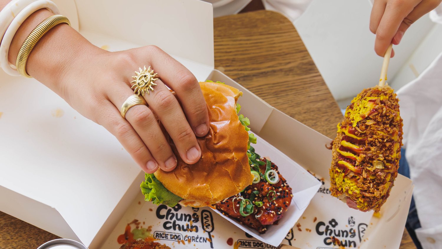 Amis partageant un plateau Chungchun : Rice Dogs, poulet croustillant, burger et frites gaufrées