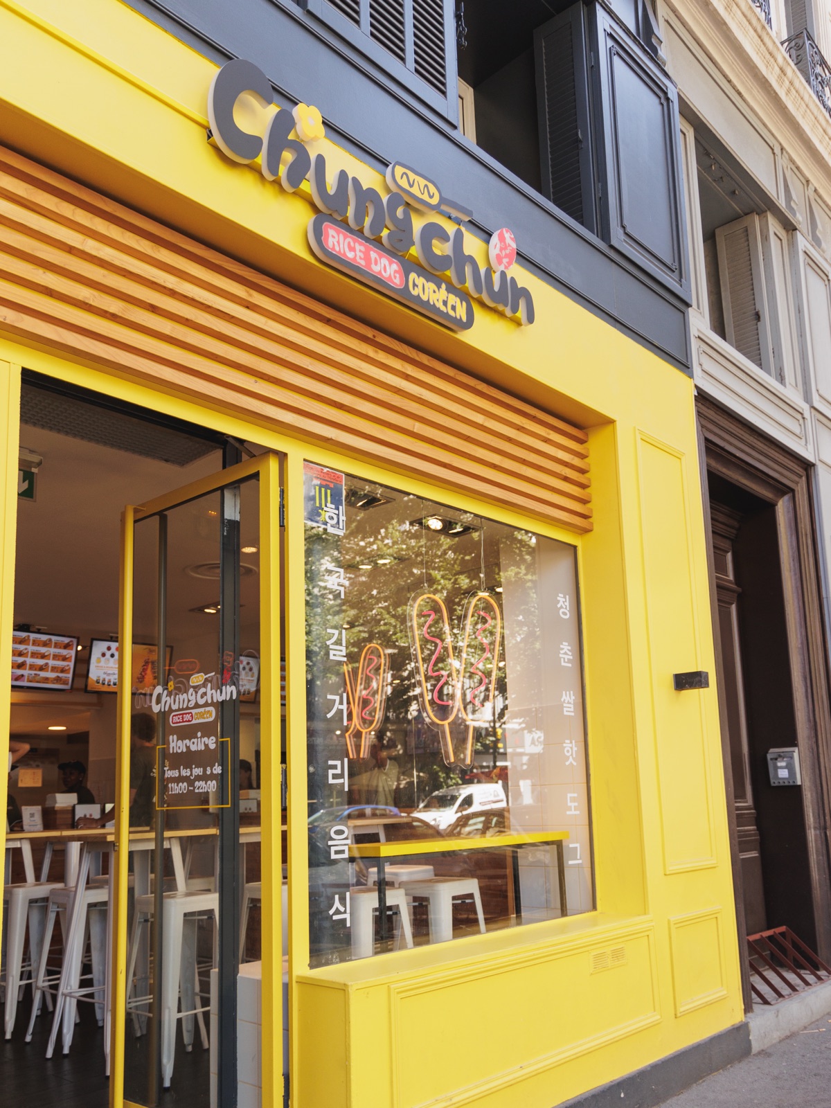 Devanture jaune vif d'un restaurant Chungchun avec enseigne Rice Dog Coréen et terrasse