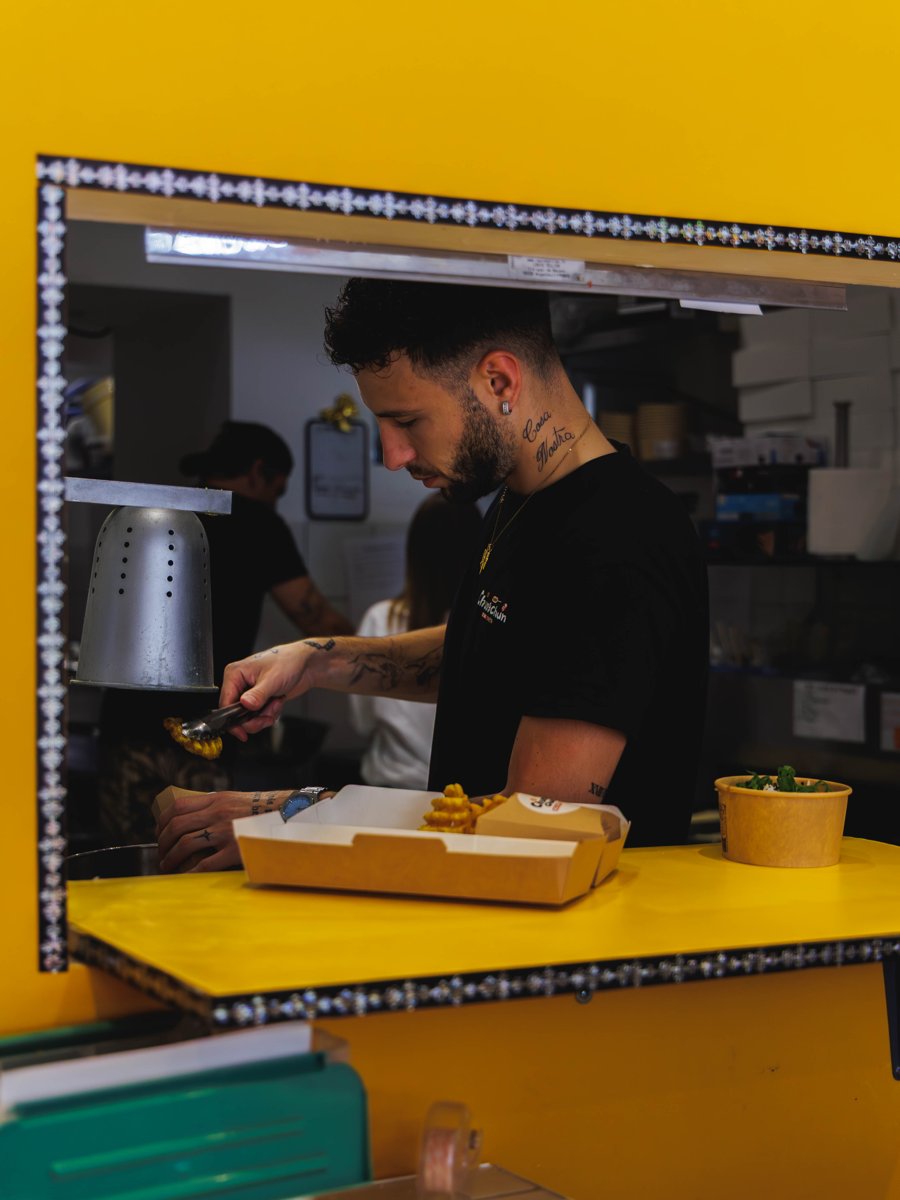 Membre de l'équipe Chungchun servant des frites gaufrées au comptoir jaune du restaurant